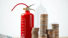 Fire safety equipment beside stacked coins, representing the HD Fire Protect stock market listing