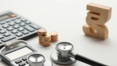 Stethoscope, calculator and coins on a desk representing health insurance tax savings